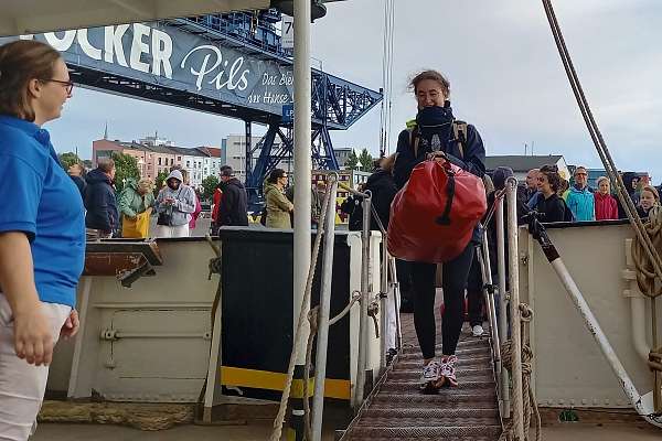Eine Schülerin trägt ihre Reisetasche über die Gangway
