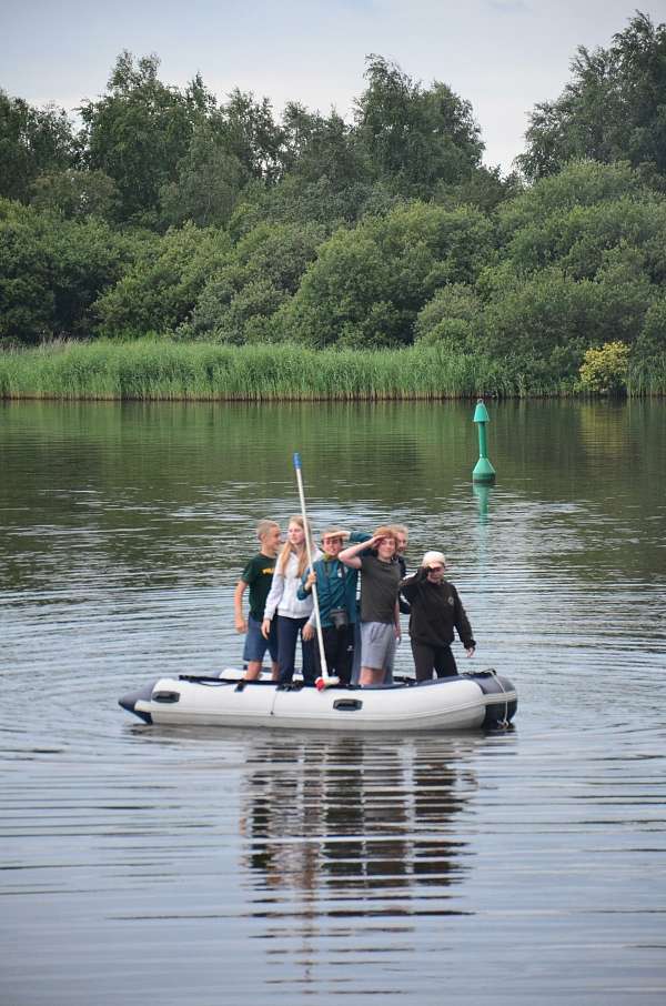 Jugendliche mit Besen auf einem Schlauchboot